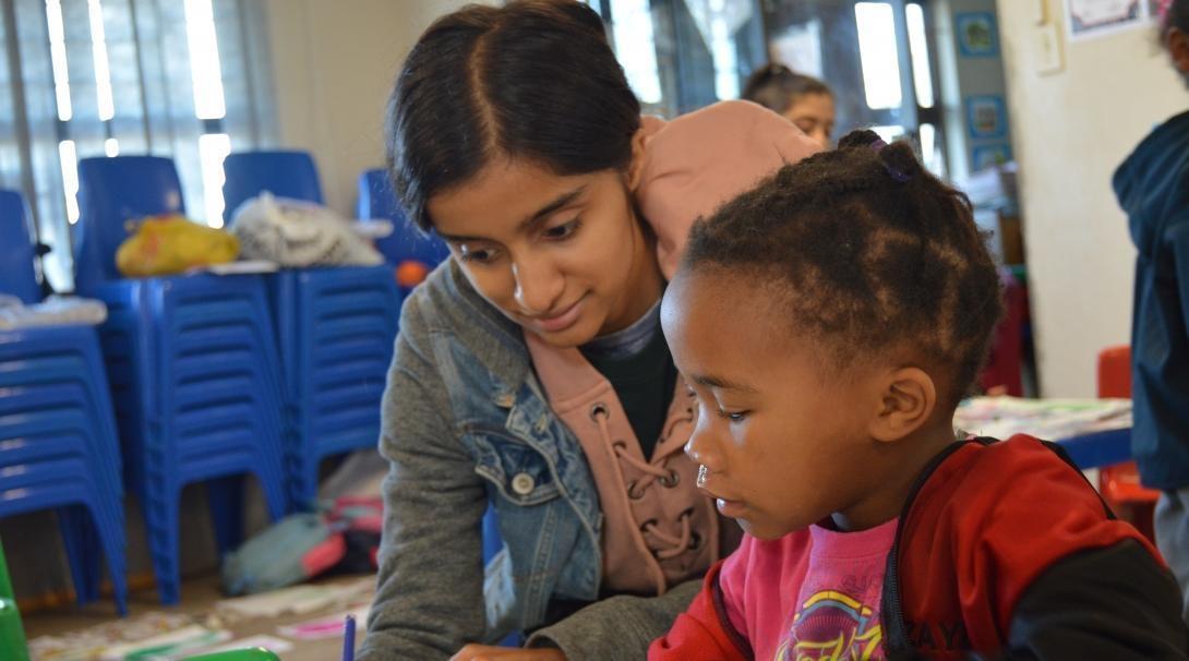 Volunteer teaching child numeracy Young volunteer helping to improve the literacy of a school child